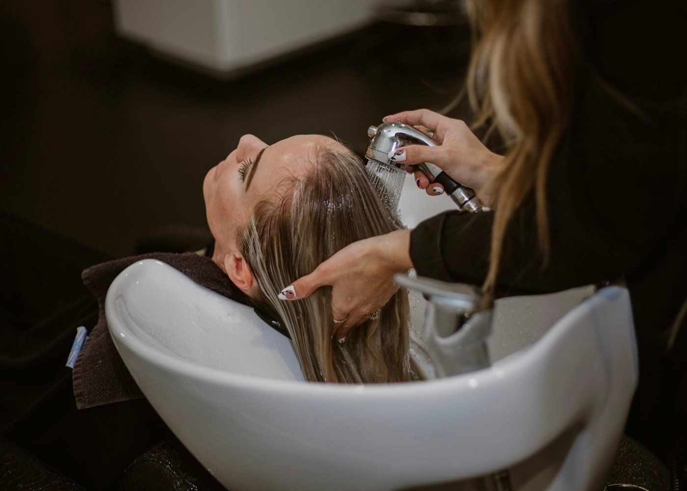 Cabeleireira cuidando do cabelo de uma cliente no salão
