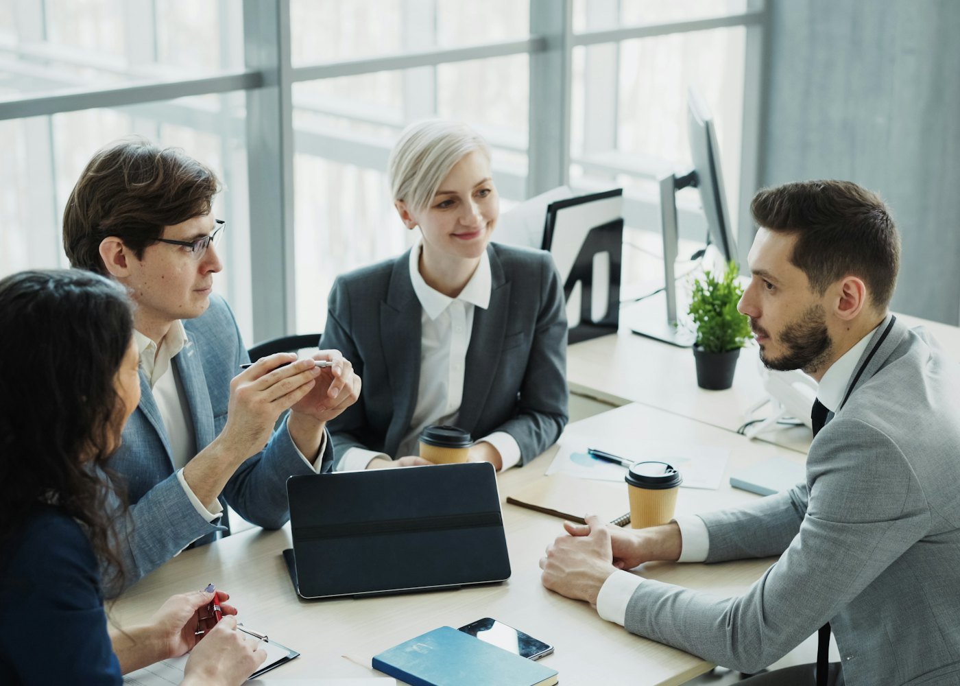 Equipe da ConTasks reunida em uma mesa de trabalho conversando sobre um projeto